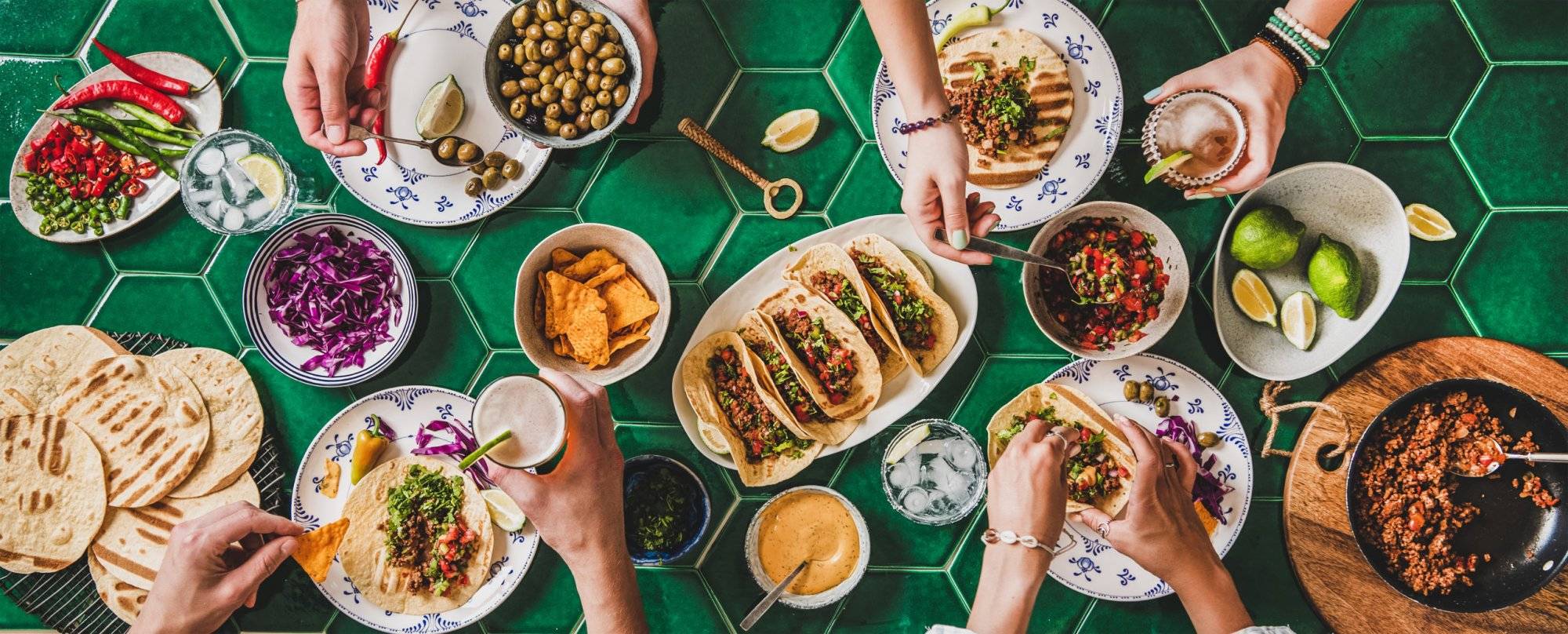 Home taco party with tortillas, tomato salsa and peoples hands