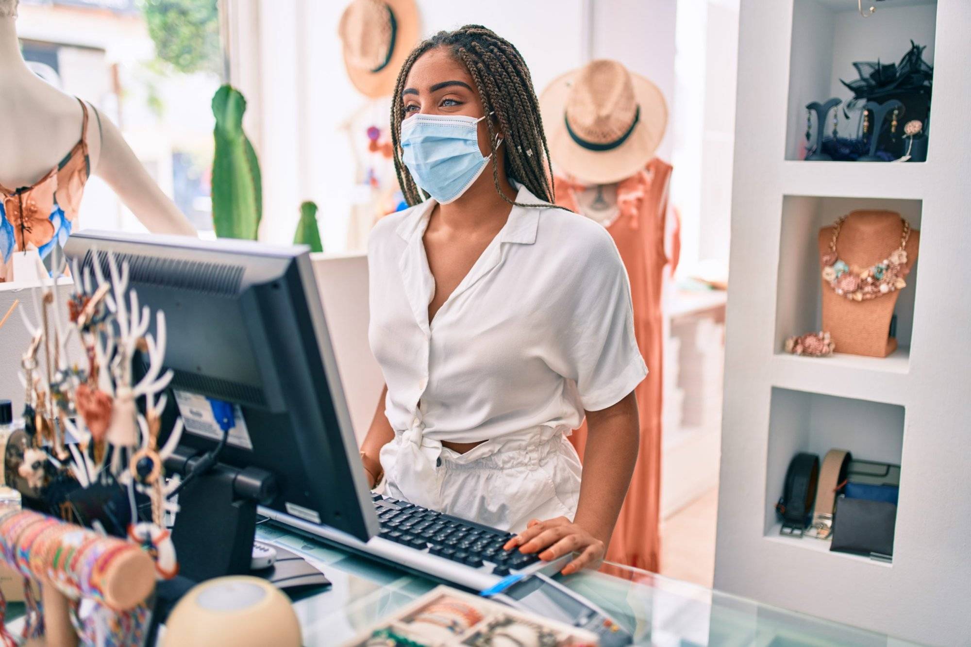 Young african american woman smiling happy working at the till wearing coronavirus safety mask at retail shop Young african american woman smiling happy working at the till wearing coronavirus safety mask at retail shop