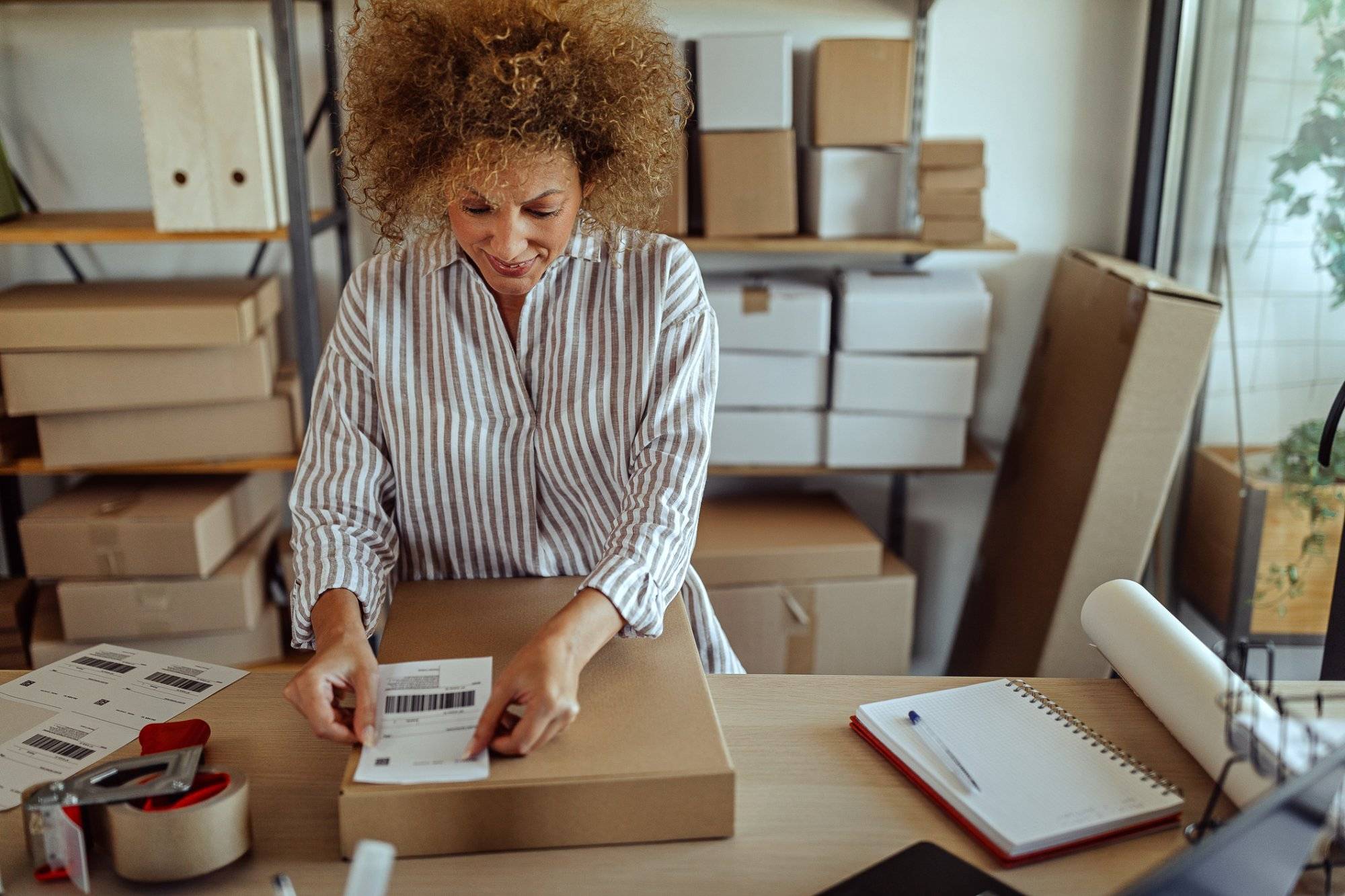 Businesswoman sticking bar code label on delivery package Businesswoman sticking bar code label on delivery package