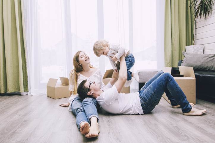 Family together happy young beautiful with a little baby moves with boxes to a new home